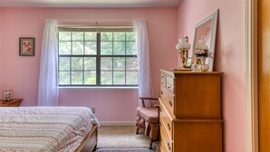 A bedroom with a large window, a bed, a dresser, and a chair. - New Braunfels Gruene River Front Property (New Braunfels)
