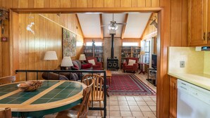 A wooden-paneled room with a dining table, chairs, a fireplace, bookshelves, and a television. - New Braunfels Gruene River Front Property (New Braunfels)