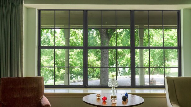 A room with a large window, a round table with decorative items, and two chairs. - New Braunfels Gruene River Front Property (New Braunfels)
