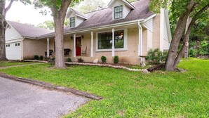 A two-story house with a front porch, a red door, and a well-maintained lawn. - New Braunfels Gruene River Front Property (New Braunfels)