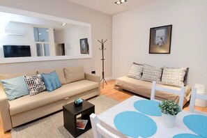Ein modernes Wohnzimmer mit einer Couch, einem Couchtisch und einem Esstisch mit blauen Platzsets.