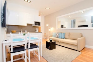 Ein modernes Wohnzimmer mit einer Couch, einem Esstisch mit Stühlen, einem Couchtisch und einem an der Wand befestigten Flachbildfernseher.