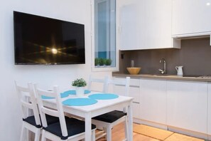 Eine kleine Küche mit weißen Schränken, einem Einbauofen und einem Fenster über der Spüle.