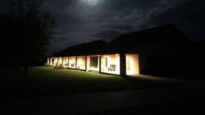 A row of illuminated rooms with a view of the moon in the sky.