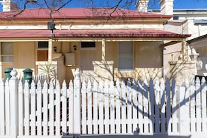 A house with a red roof, white picket fence, and a mailbox.