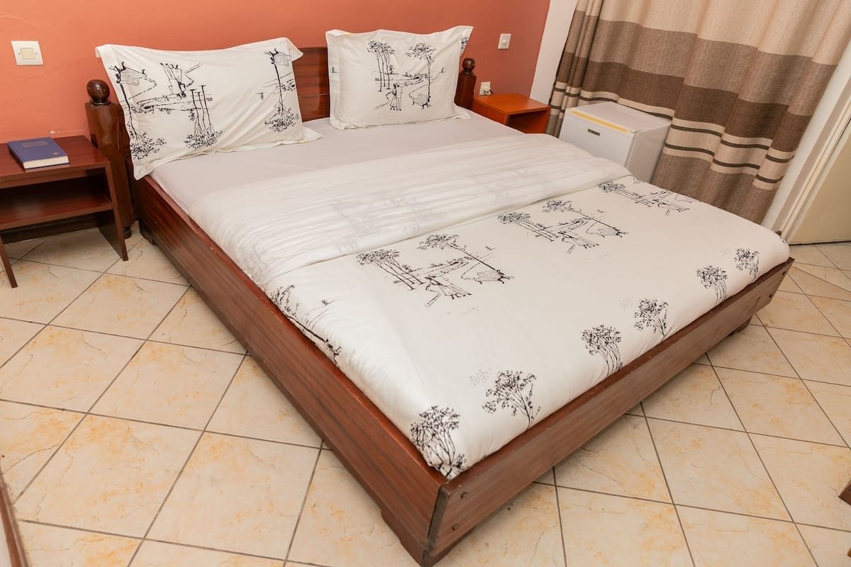 A neatly made bed with a floral bedspread, wooden headboard, and matching pillows.