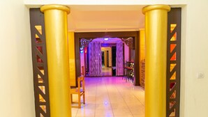 A corridor with golden pillars and purple curtains leading to a room. - Perle Boutique Hotel (Kigali)