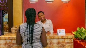 A reception desk with a marble top, a clock, and a sign indicating accepted credit cards. - Perle Boutique Hotel (Kigali)