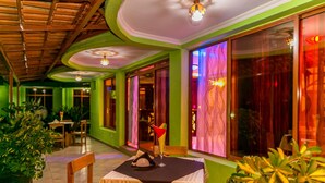 A restaurant with a green and white color scheme, wooden chairs, and a table set with a black tablecloth. - Perle Boutique Hotel (Kigali)