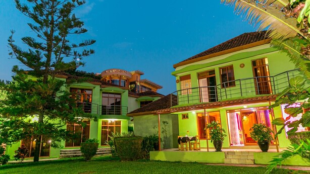 A two-story house with a balcony, a covered patio, and a well-maintained lawn. - Perle Boutique Hotel (Kigali)