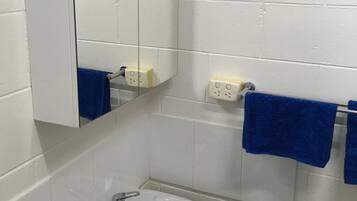 A bathroom with a white sink, a mirror, and two blue towels hanging on a rack.