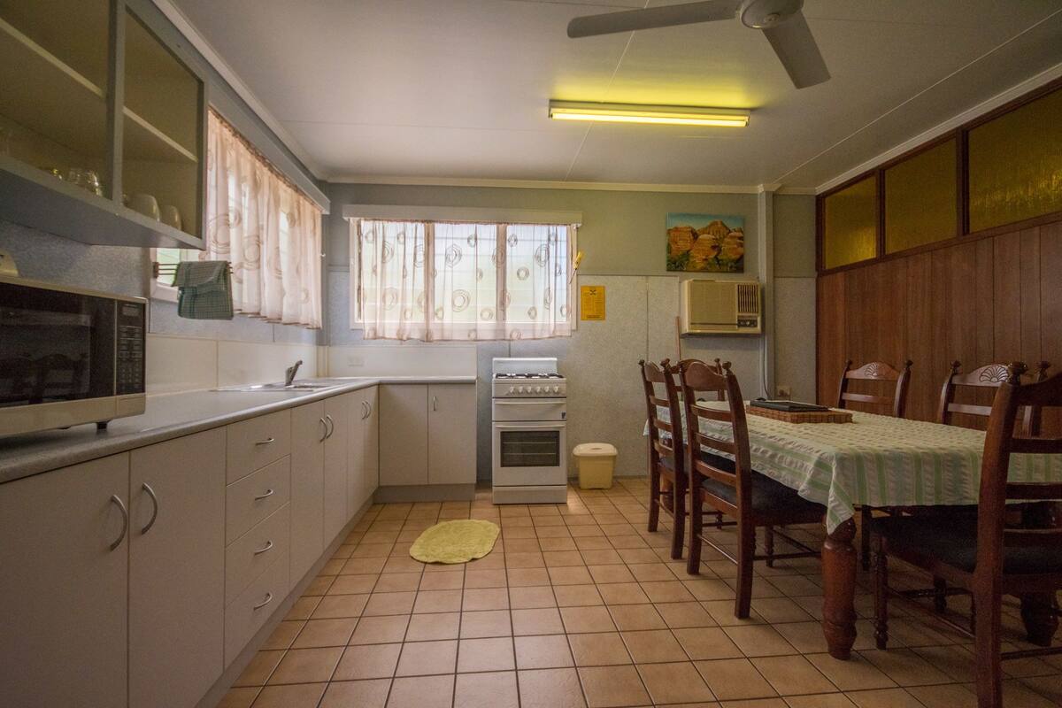 Cocina compacta con comedor, que incluye microondas, estufa y mesa de comedor con sillas.