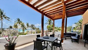 Eine Terrasse im Freien mit einer Holz-Pergola, einem Tisch mit Stühlen und einer Sitzecke.