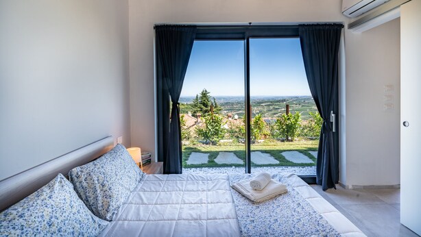 A bedroom with a large bed, a view of a garden, and an air conditioning unit. - ONE BEDROOM HOLIDAY FLAT WITH VIEW (Diano d'Alba)