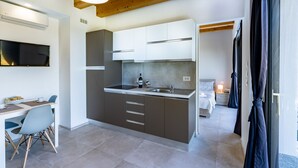 A modern kitchen with a central island, built-in cabinets, and a dining area with a table and chairs. - ONE BEDROOM HOLIDAY FLAT WITH VIEW (Diano d'Alba)
