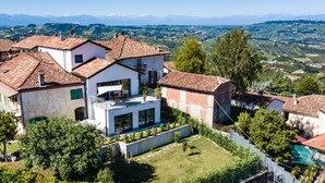 A modern villa with a spacious balcony, surrounded by lush greenery and a scenic mountainous backdrop. - ONE BEDROOM HOLIDAY FLAT WITH VIEW (Diano d'Alba)