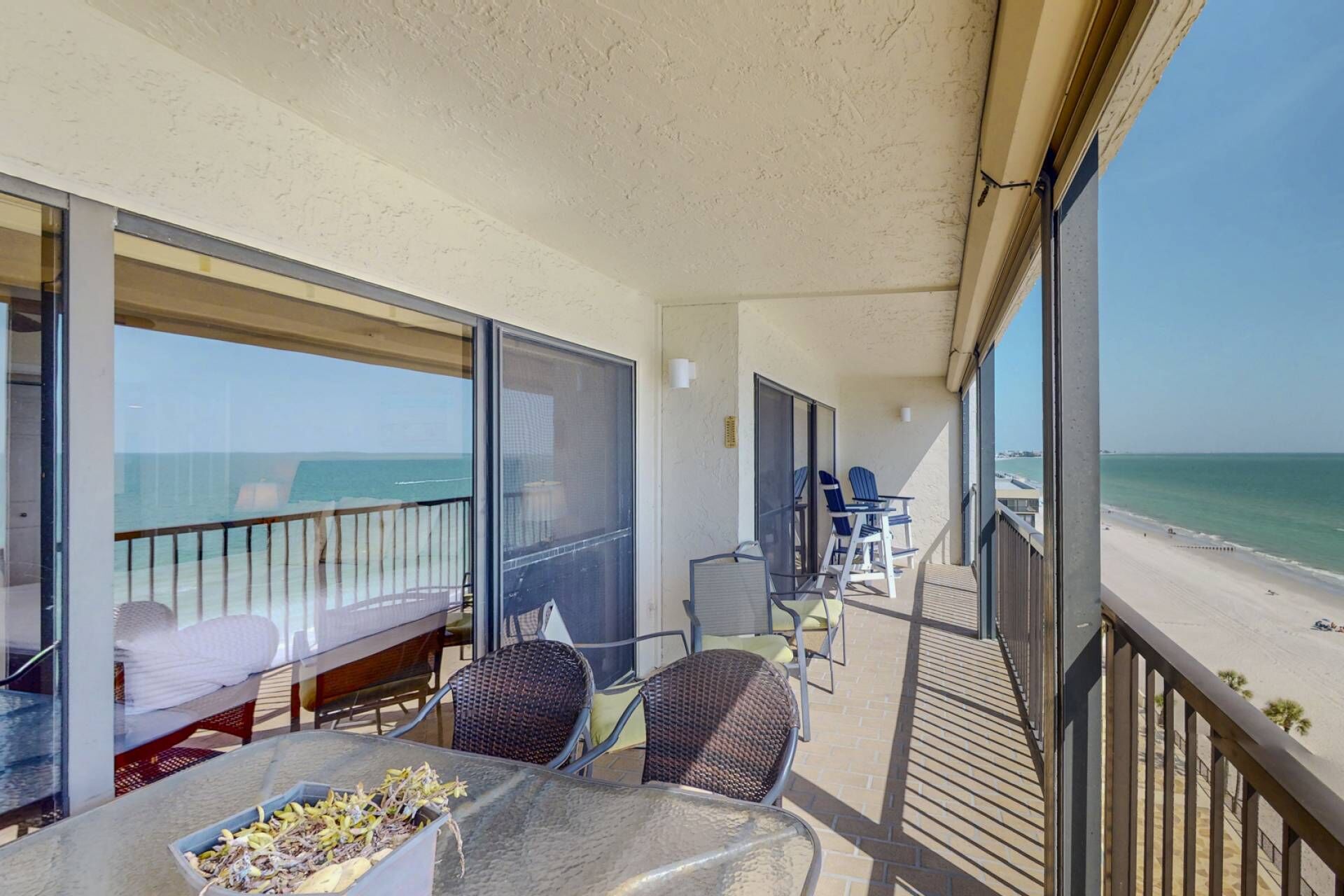 Ein Balkon mit Tisch, Stühlen und Blick auf Strand und Meer.