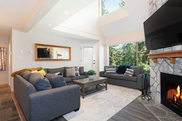 Living room has vaulted ceilings, fireplace, and golf course views