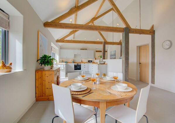 Enjoy meals in this dining area with a table for four, surrounded by comfortable chairs and a functional kitchen.