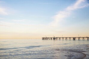 Eine Pier, die sich in ruhiges Wasser erstreckt, mit blauem Himmel.