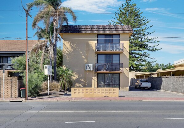 A two-story building with a balcony, a parking area, and a street view.