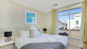 Hotelkamer met een bed, twee nachtkastjes, een raam met gordijnen, een hoofdeinde en een aan de muur hangend schilderij.