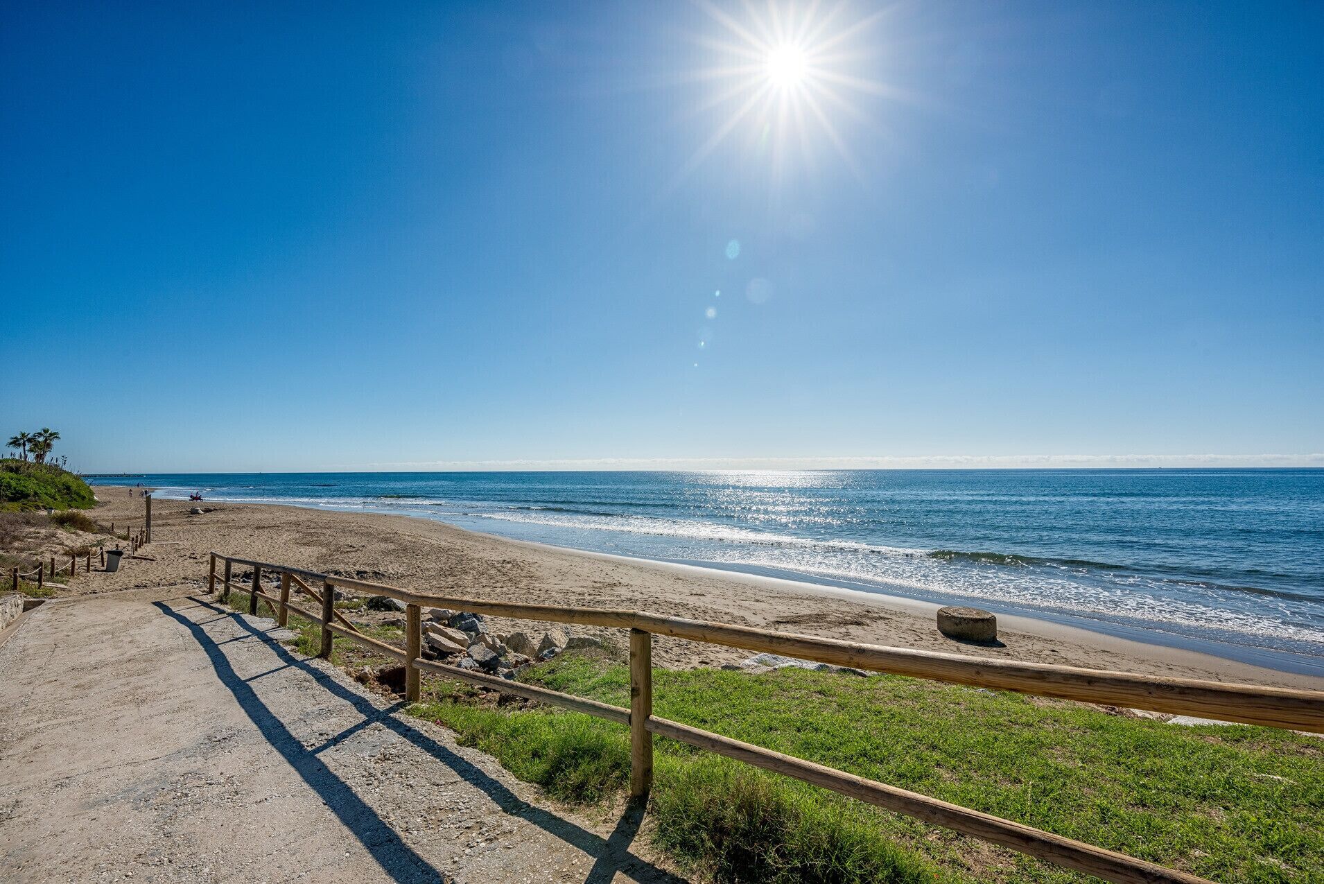 A beach path with wooden railings leading to the ocean.