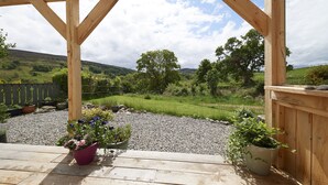 Une pergola en bois, un chemin de gravier et des plantes en pot.
