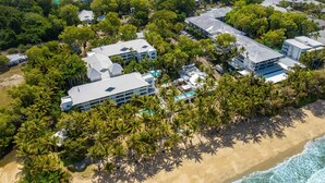 An aerial view of a resort with multiple buildings, a swimming pool, and a beach.