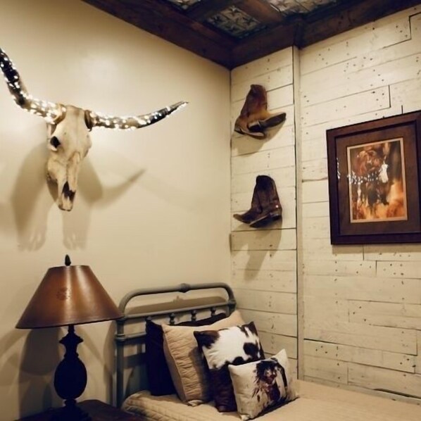 A room with a bed, a lamp, a wall-mounted deer head, and a framed picture. - Cowboy corral at Rockin' star ranch (Brenham)