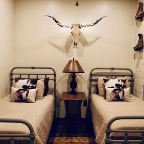 A room with two beds, a lamp, and a wall-mounted skull. - Cowboy corral at Rockin' star ranch (Brenham)