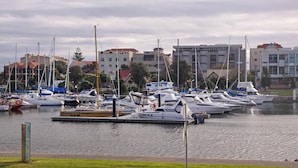 A marina with multiple boats docked, surrounded by buildings and greenery. - Riverside Courtyard Glenelg North | Pets Welcome (Glenelg North)