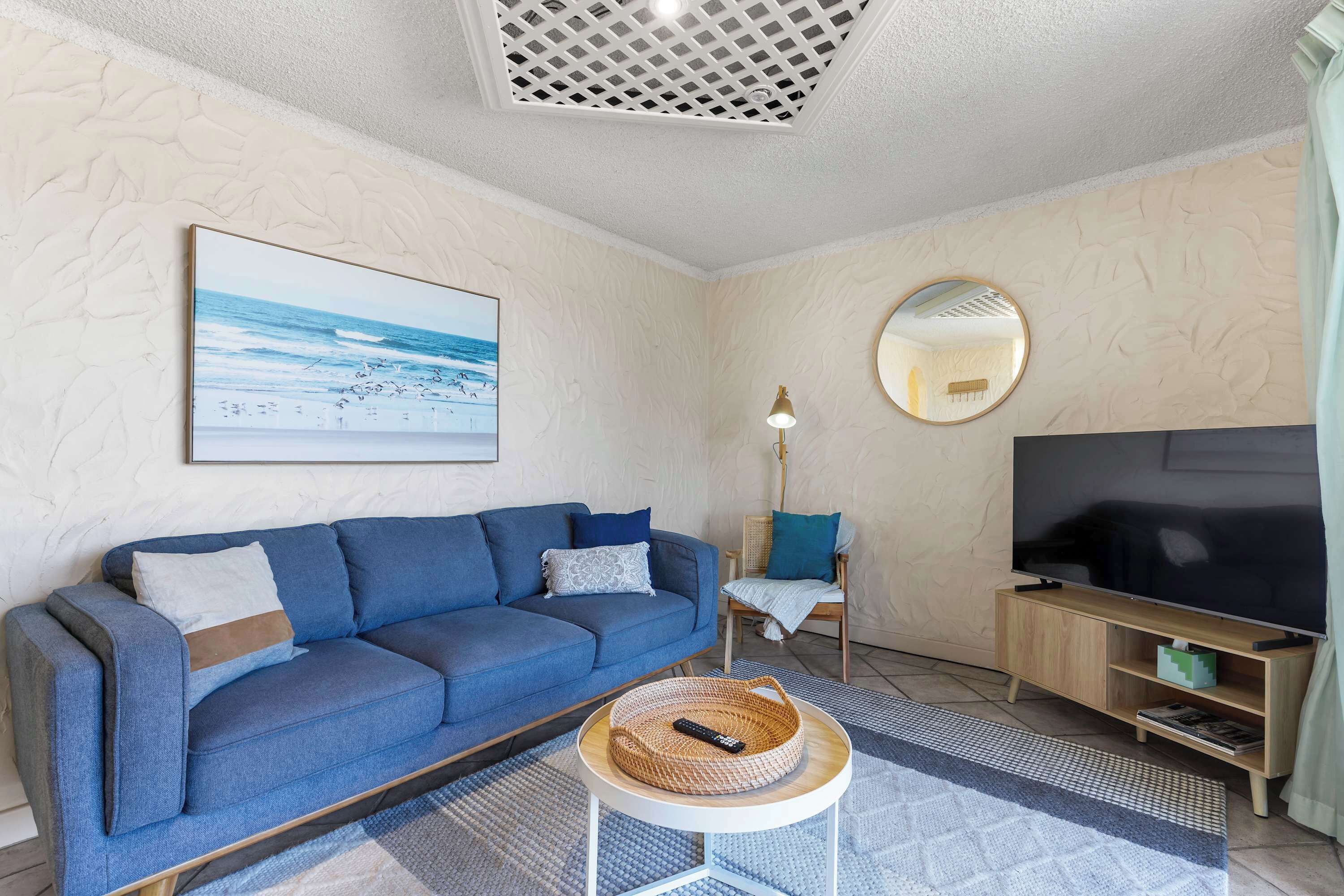 A living room with a sofa, a TV, a lamp, and a framed picture on the wall.
