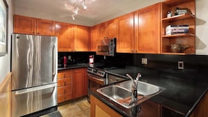 A kitchen with wooden cabinets, stainless steel appliances, and a black countertop.