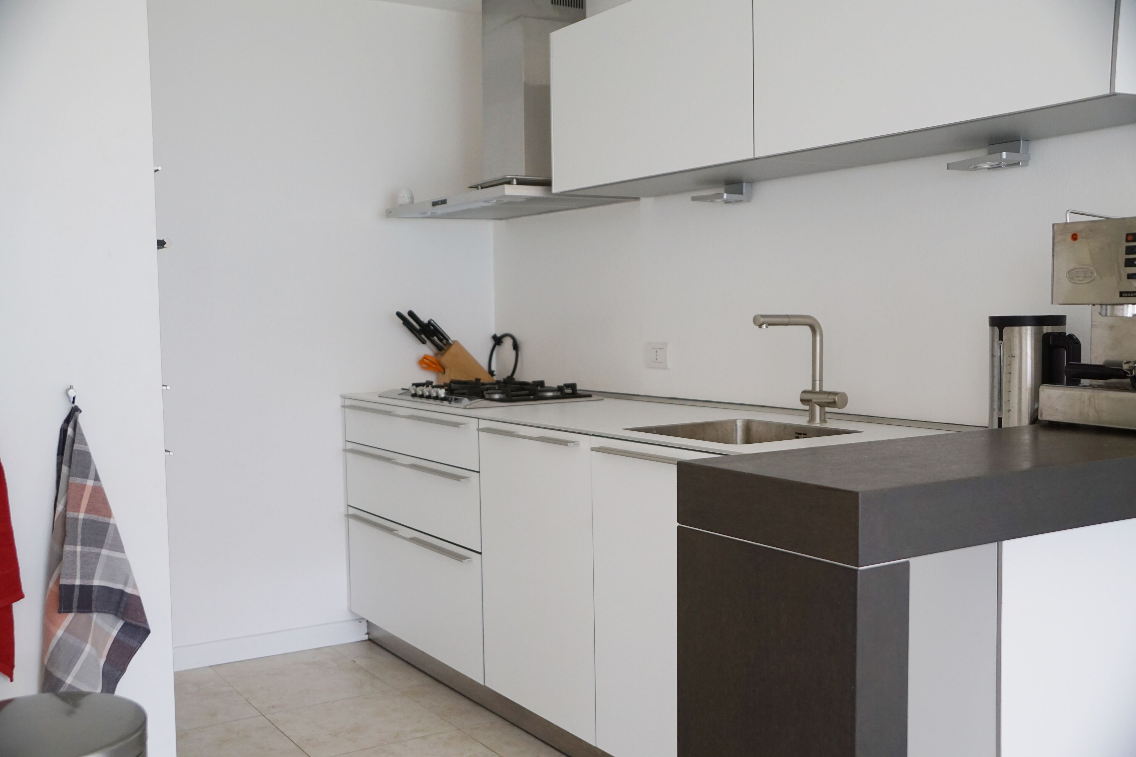 A modern kitchen with white cabinets, a stainless steel sink, and a black countertop.