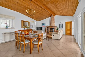 Un amplio espacio de sala con mesa de comedor, sillas, chimenea y televisor.