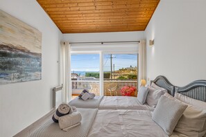A bedroom with a bed, a window with curtains, a radiator, and a painting on the wall.