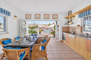 A modern kitchen with a dining area, a view of the neighborhood, and a pool.