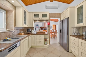 A modern kitchen with a central island, built-in appliances, and a dining area with a wooden table and chairs.