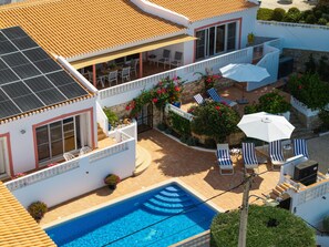 A residential property with a swimming pool, outdoor seating, and solar panels.