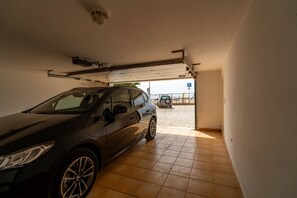 A car parked inside a garage with a tiled floor and a garage door.