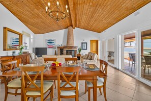 A dining area with a wooden table and chairs, a television, and artwork on the walls.