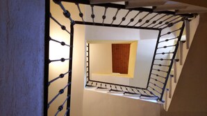Un escalier en colimaçon avec un panneau central en bois, des rampes en métal et un mur de couleur beige.