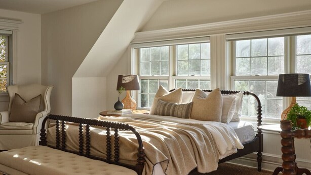 Un dormitorio con cama, banco y ventana con vistas.