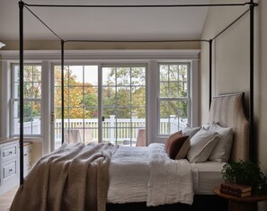 Une chambre à coucher avec un lit à baldaquin, de grandes fenêtres et une vue sur une terrasse.