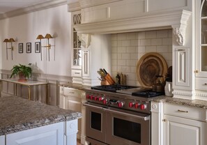 Une cuisine équipée d’une cuisinière à gaz, d’un four et d’un plan de travail en marbre.