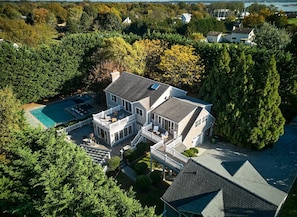 Ein großes, zweistöckiges Haus mit Schwimmbad, mehreren Terrassen und einem gepflegten Garten.