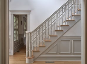 A staircase with white railings and wooden steps, leading to a landing with a door.