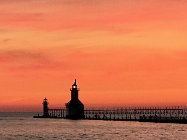 Un paysage côtier avec un phare et une jetée, au coucher du soleil.