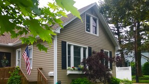 A two-story house with a front porch, a wooden staircase, and a garden with various plants. - Historic and quiet St. Joseph neighborhood: Lovely comfortable 100 yo two story (St Joseph)